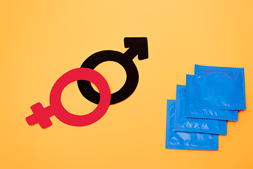 top view of gender symbols near condoms isolated on orange