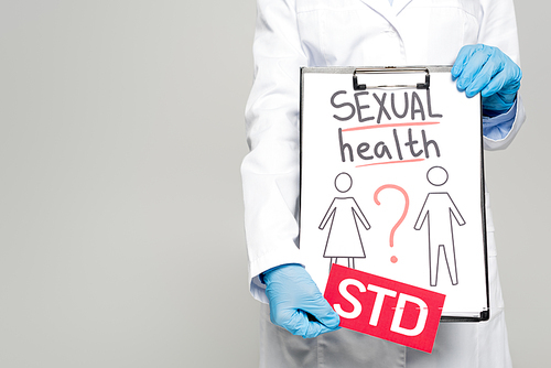 cropped view of doctor in blue latex gloves and white coat holding clipboard with sexual health, drawn man and woman and std lettering isolated on grey