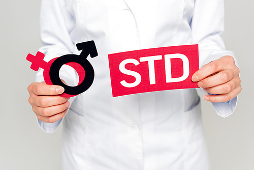cropped view of doctor in white coat holding gender symbols and std lettering isolated on grey