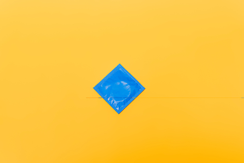 top view of blue pack with condom isolated on orange