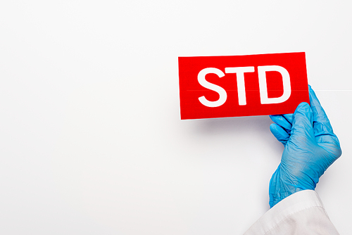 cropped view of doctor in blue latex glove holding paper with std lettering on white