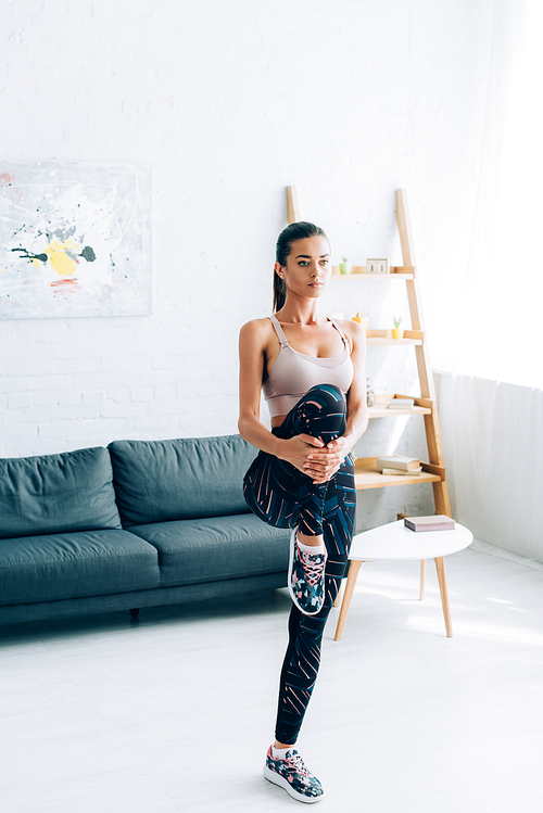 Young sportswoman warming up while exercising at home