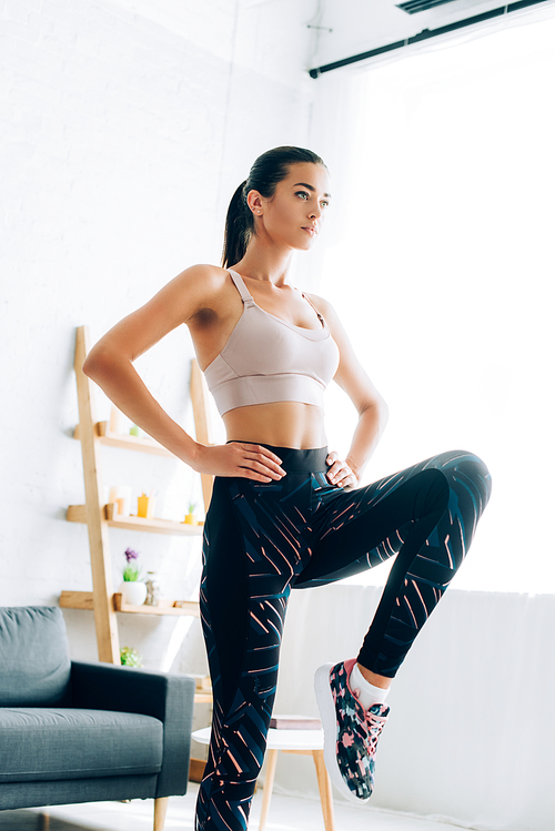 Brunette sportswoman with hands on hips working out in living room