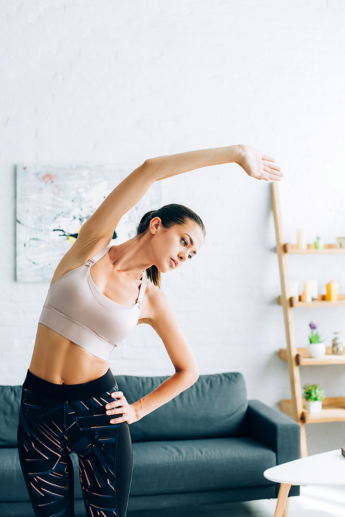 Brunette sportswoman with hand on hip exercising in living room