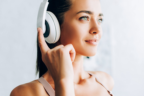 Selective focus of brunette woman listening music in headphones in living room