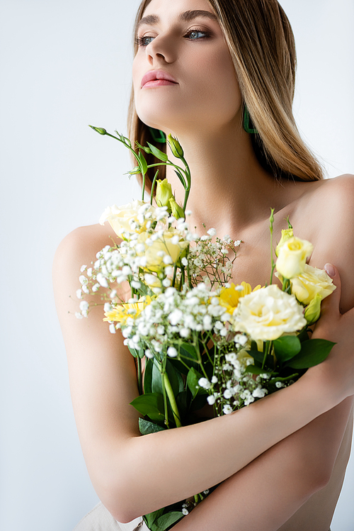 young model with naked shoulders embracing flowers on white