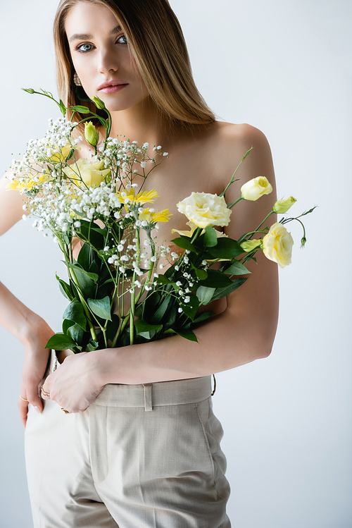 young woman with flowers in pants  while posing on white