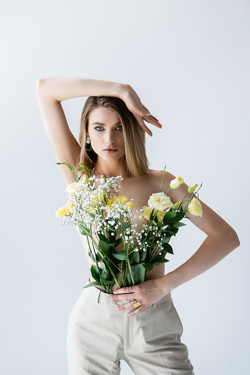 young model with bouquet of flowers in pants posing on white