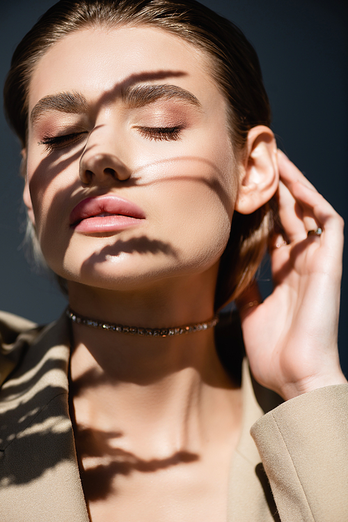 wheat spikelets shadows on face of young woman with closed eyes on dark grey background