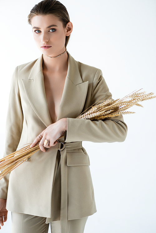 young woman in beige formal wear holding ripe wheat on white