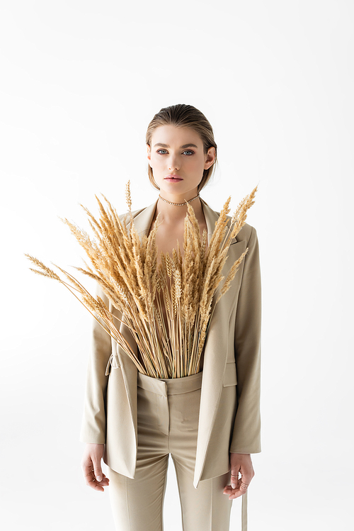 stylish model in beige suit with wheat spikelets posing isolated on white