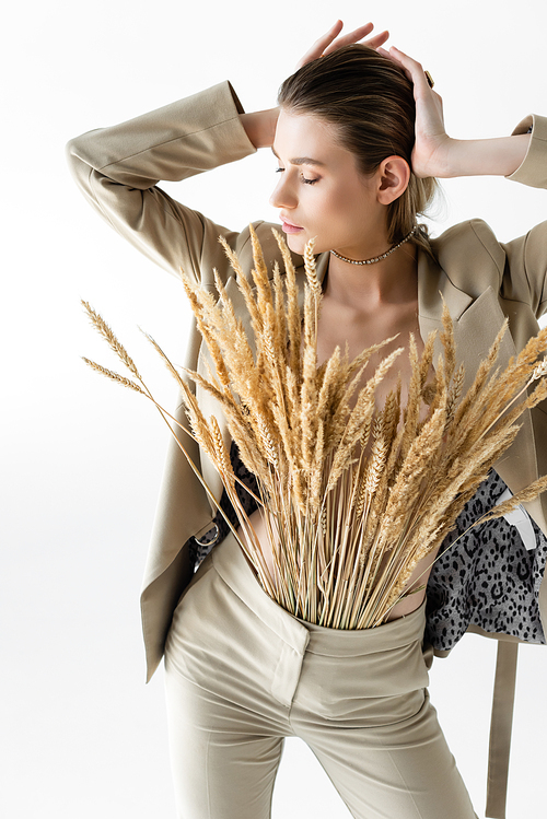 stylish model in beige formal wear with wheat spikelets posing isolated on white