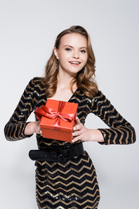 young cheerful woman holding christmas present isolated on grey