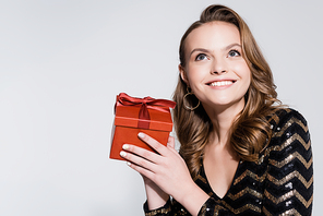 positive woman holding christmas present isolated on grey