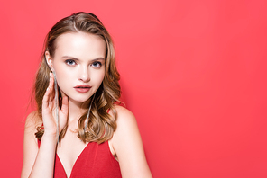 young woman touching earring and  isolated on red