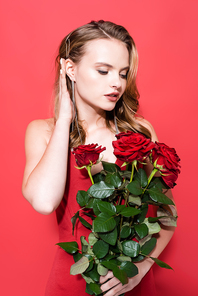 young woman looking at roses and fixing hair on red