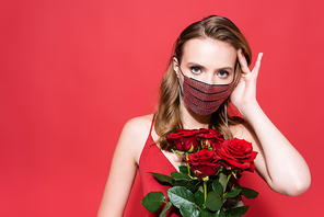 young woman in protective mask with rhinestones holding roses and  on red