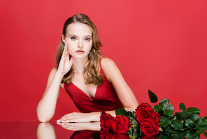 young woman  near roses on red