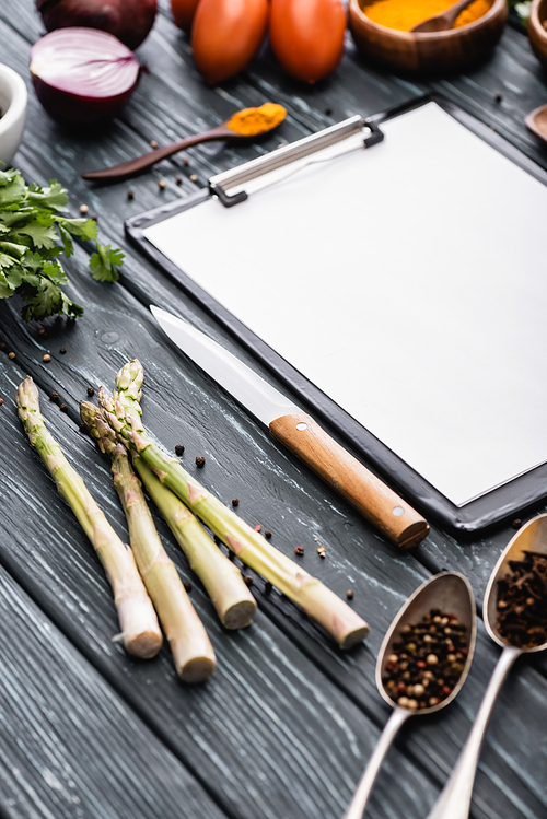 selective focus of blank clipboard near knife and vegetables on wooden surface