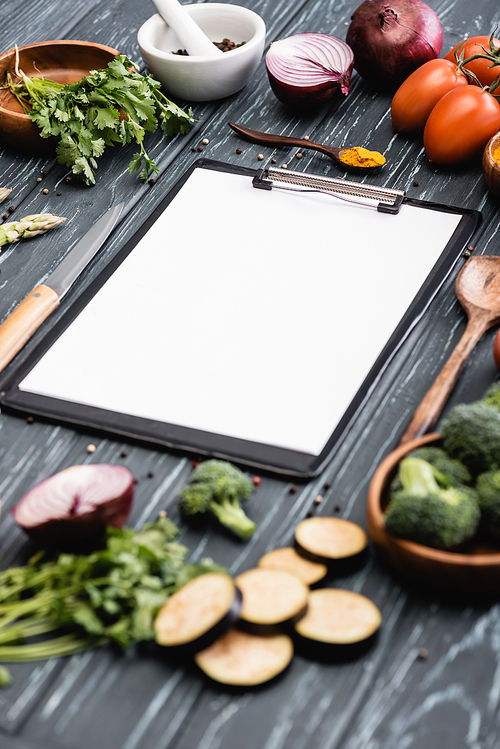selective focus of blank clipboard near spices and vegetables on wooden surface