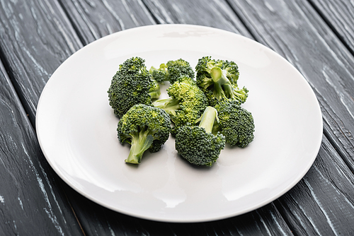 fresh green broccoli on white plate on wooden surface