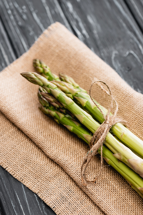 fresh green asparagus on burlap on wooden surface