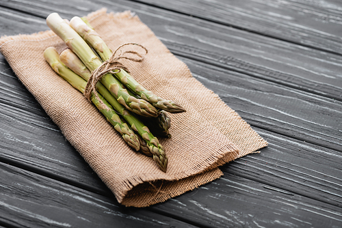 bundle of fresh green asparagus on burlap on wooden surface