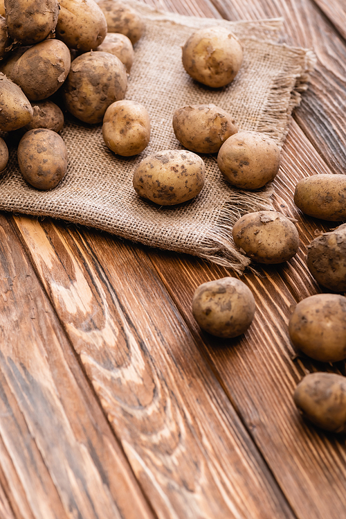 dirty potatoes and burlap on wooden table
