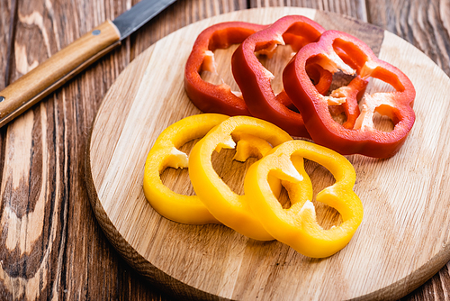 colorful sliced bell peppers on wooden cutting board near knife
