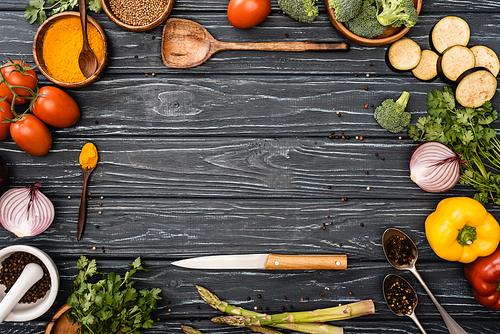 top view of fresh colorful vegetables, spices near knife and spatula on wooden surface