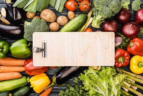 top view of fresh colorful vegetables around empty wooden clipboard