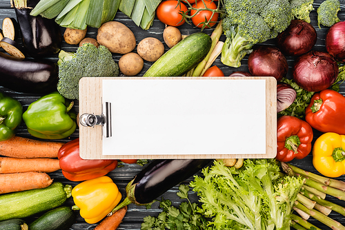top view of fresh colorful vegetables around empty clipboard with paper