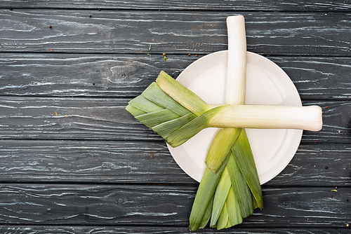 top view of fresh green leek on plate on wooden surface