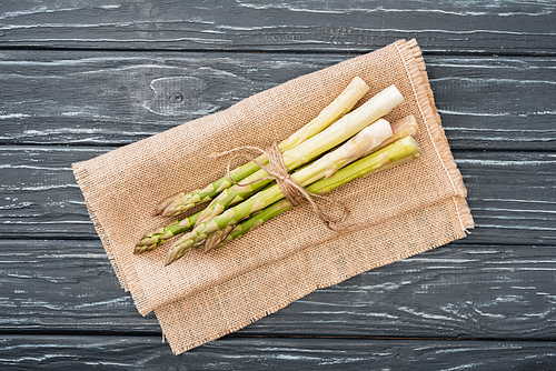 top view of fresh asparagus on burlap on wooden surface