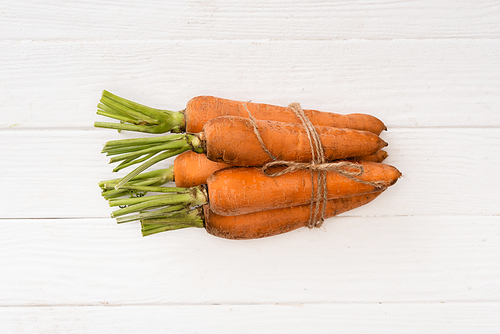 top view of carrots tied with rope on white wooden table
