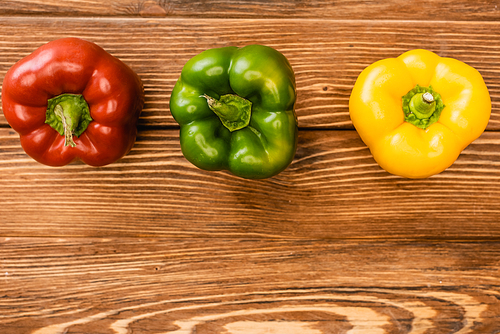 top view of colorful ripe bell peppers on wooden table