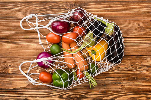 top view of fresh ripe vegetables in string bag on wooden table