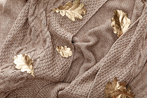 top view of knitted brown sweater with golden painted leaves