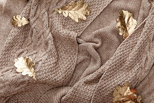 top view of golden foliage scattered on knitted brown sweater
