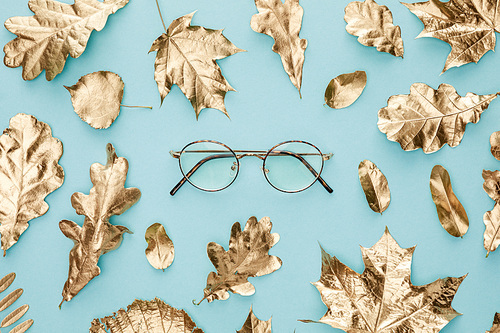 top view of autumnal golden foliage and glasses on blue background