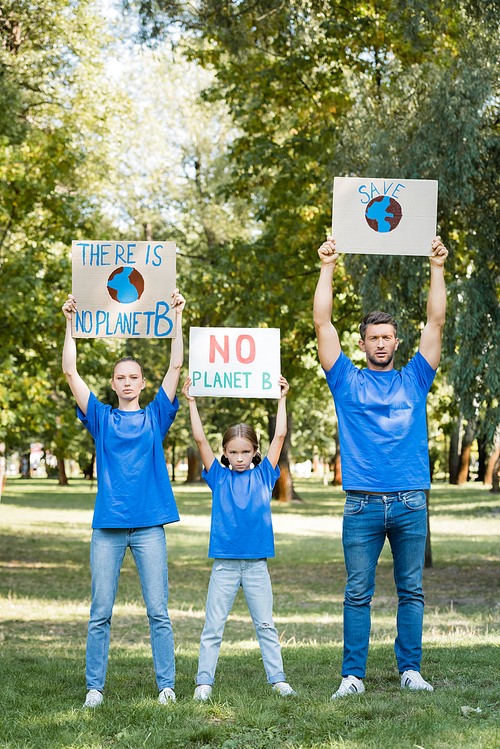 family of activists holding placards with globe, save, and no planet b inscription in raised hands, ecology concept