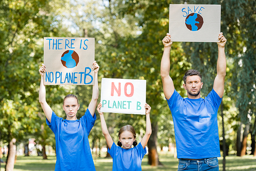 family of volunteers holding placards with globe, save, and no planet b inscription in raised hands, ecology concept