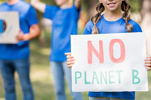 cropped view of girl holding placard with no planet b inscription near mother and father on blurred background