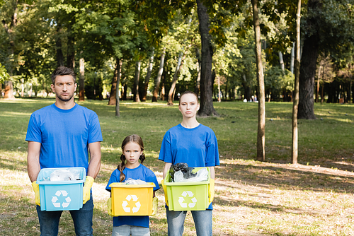 family of volunteers holding containers with recycling symbols, full of plastic waste, ecology concept