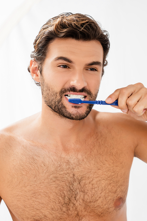 Bearded man looking away while brushing teeth in bathroom