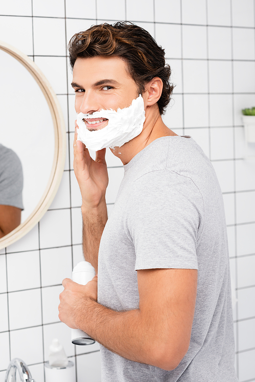 Smiling man applying shaving foam in bathroom