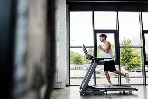 selective focus of handsome sportsman running on treadmill in gym