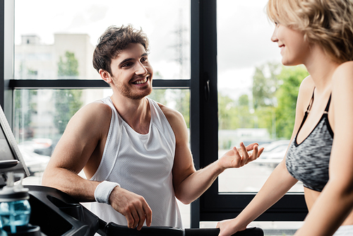 selective focus of happy sportsman looking at girl in gym