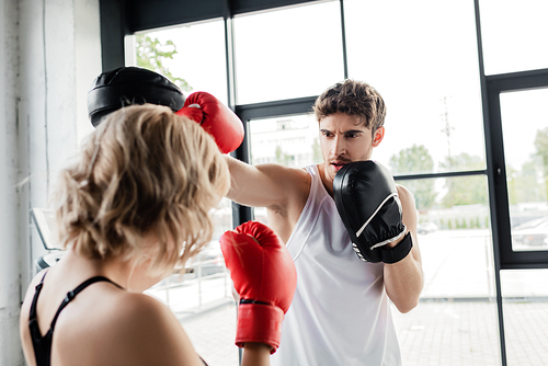 selective focus of sport couple in boxing gloves and pads exercising in gym