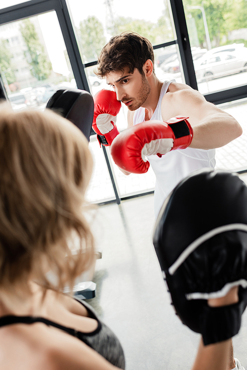 selective focus of sport couple in boxing gloves and boxing pads training in gym